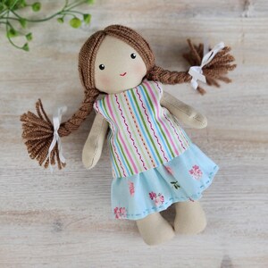 Handmade cloth doll wearing striped top and blue floral skirt outfit made from sewing pattern