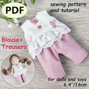May include: A doll clothing set, including a white blouse with pink heart and bunny designs, lace trim, and pink trousers. The set is designed for dolls and toys, with a size of 6.4 inches or 16cm. The image also includes the text "PDF", "sewing pattern and tutorial", and "Blouse + Trousers".