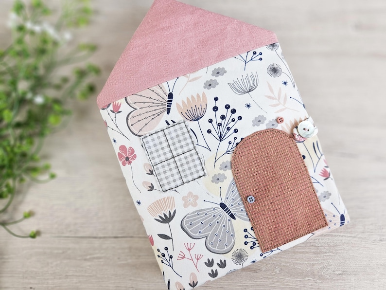Front view of soft fabric dollhouse, textile toy house with pink roof, door and window details