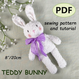 May include: A white teddy bunny plush toy with a purple ribbon, pink cheeks, and a pink nose. The bunny is 8 inches (20cm) tall. The image includes the text "PDF sewing pattern and tutorial" and "TEDDY BUNNY".