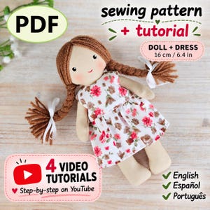 May include: A fabric doll with brown yarn hair in two braids tied with white ribbons, wearing a white dress with a red and brown floral pattern. The doll measures 16 cm / 6.4 in. Text includes PDF, sewing pattern + tutorial, and 4 video tutorials.