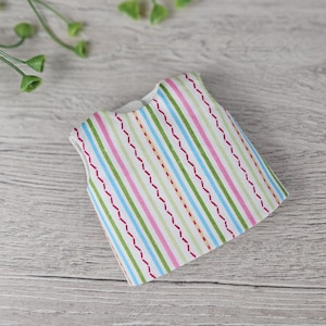 Striped doll top sewing piece displayed flat on wooden background