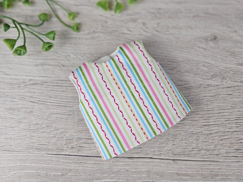 Striped doll top sewing piece displayed flat on wooden background