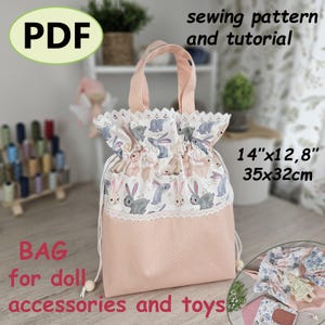 Puede incluir: Una bolsa rosa y blanca con cordón y estampado de conejos, diseñada para accesorios y juguetes de muñecas. La bolsa mide 35cm x 32cm. El texto "PDF" y "patrón de costura y tutorial" son visibles.