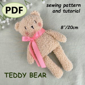 Può includere: Un orsacchiotto beige con un nastro rosa, di 20 cm. L'orso ha bocca e occhi cuciti, con guance rosa. Il testo sull'immagine recita "PDF", "modello di cucito e tutorial" e "TEDDY BEAR".