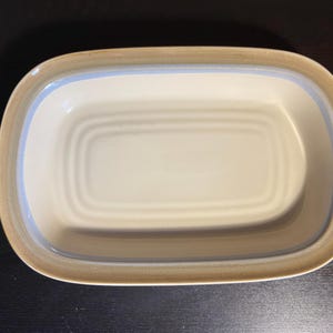 May include: A rustic wooden sign with the text "Welcome" in a handwritten style. The sign is painted white with a distressed finish, and a small, decorative heart is attached to the bottom. The background is a blurred image of a wooden surface.