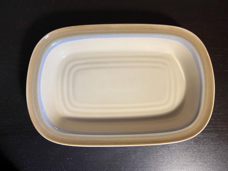 May include: A rustic wooden sign with the text "Welcome" in a handwritten style. The sign is painted white with a distressed finish, and a small, decorative heart is attached to the bottom. The background is a blurred image of a wooden surface.