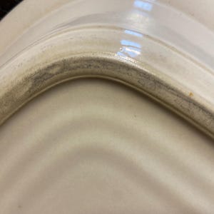 May include: A white ceramic mug with a black handle and the text "But First, Coffee" in a bold, black font. The mug is set against a neutral background, highlighting its simple design.