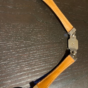 May include: A vintage belt featuring a combination of silver-toned metal and tan leather. The belt has a series of decorative metal links and rectangular leather sections. The leather is stitched with a contrasting thread. The belt is designed to be worn around the waist.