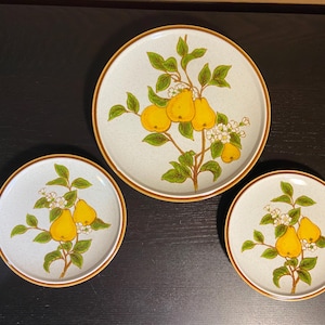 Puede incluir: Juego de tres platos de cerámica con diseño de pera. Los platos tienen un fondo azul claro y un borde marrón. El diseño incluye peras amarillas, hojas verdes y flores blancas.