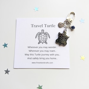May include: A silver travel turtle keyring with a blue crystal charm. The keyring comes with a card that reads "Travel Turtle" and a poem about safe travels.