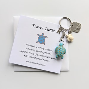 Può includere: Un portachiavi a forma di tartaruga turchese con un ciondolo d'argento che dice "Dreaming of the Sea". Il portachiavi ha anche un ciondolo d'argento con la lettera "R" e un piccolo ciondolo a forma di tartaruga bianca. Il portachiavi viene fornito con una carta che dice "Travel Turtle" e una poesia sul viaggio.