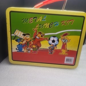 May include: A vintage metal lunch kit with a yellow frame and a red handle. The front features cartoon characters and the words "METAL LUNCH KIT" in a colorful design. The background is green, yellow, and red.