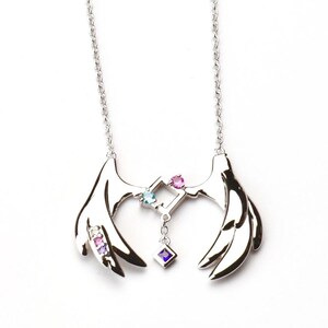 May include: Silver necklace with a pair of wings and a square pendant with colorful gemstones. The pendant has a small chain with a single gemstone hanging from it.
