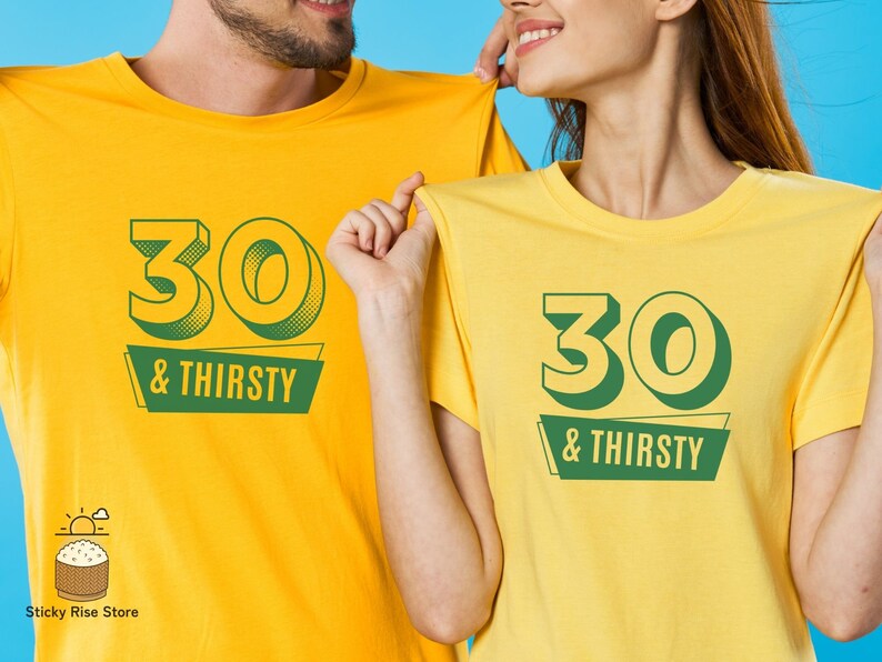 May include: Two yellow t-shirts with the text "30 & THIRSTY" in green. The number "30" has a 3D effect. The shirts are being held up by two people. The background is a solid blue.