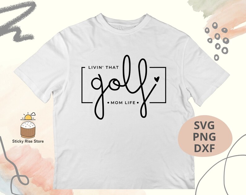 May include: White t-shirt with black text that says "Livin' that golf Mom Life" with a heart symbol.