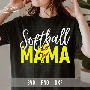 Può includere: Maglietta nera con il testo "Softball Mama" in lettere bianche e gialle. Un fulmine giallo con una palla da softball rossa si trova al centro della parola "Mama". Il testo "SVG | PNG | DXE" è in fondo alla maglietta.