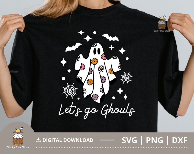 Pu&ograve; includere: Maglietta nera con un design di fantasma bianco con fiori rosa, arancioni e viola. Il fantasma &egrave; circondato da stelle e ragnatele. Il testo "Let's go Ghouls" &egrave; stampato sotto il fantasma.