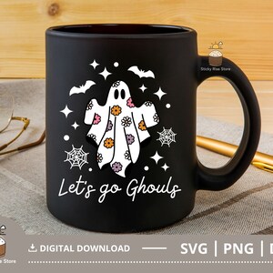 Pu&ograve; includere: Tazza da caff&egrave; nera con un fantasma bianco che indossa un motivo floreale e il testo "Let's go Ghouls".