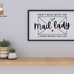 May include: Black and white framed wall art with the text "Don't mess with the mail lady I know where you live" with a red heart and a paper airplane illustration.