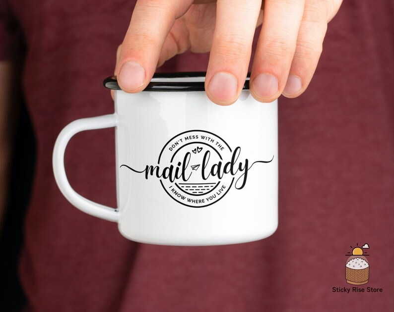 May include: White enamel mug with a black rim and handle. The mug has a black and white graphic that says "Don't mess with the mail lady I know where you live".