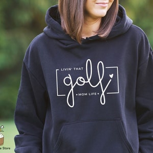 May include: Black hooded sweatshirt with white text that reads "Livin' that golf mom life."