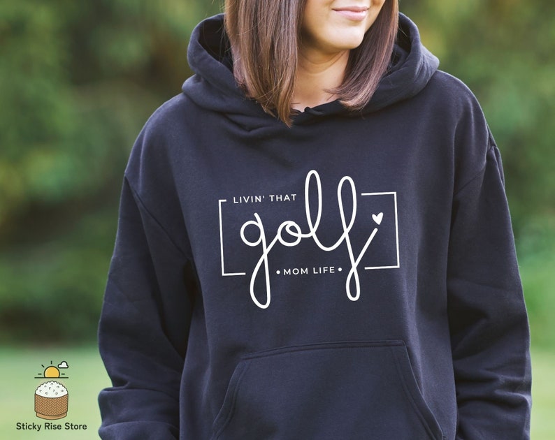 May include: Black hooded sweatshirt with white text that reads "Livin' that golf mom life."