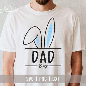 Op de afbeelding: Wit T-shirt met een zwarte omtrek van konijnenoren en de tekst "DAD Bunny" in zwart. De konijnenoren hebben een blauwe binnenkant. Onderaan het shirt staat de tekst "SVG | PNG | DXF" in zwart.