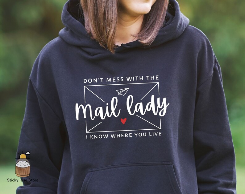 May include: A dark blue hoodie with a white graphic that says "Don't mess with the mail lady I know where you live". The graphic is in the shape of an envelope with a paper airplane inside.