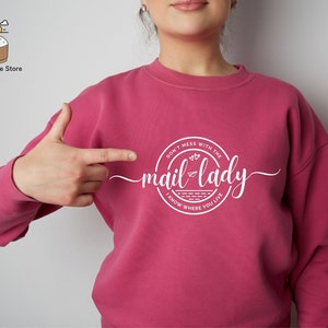 May include: Pink sweatshirt with a white graphic that says "Don't mess with the mail lady I know where you live".