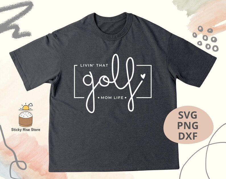 May include: A dark gray t-shirt with the text "LIVIN' THAT golf &bull; MOM LIFE." in white. The text is in a handwritten style with a heart symbol.