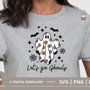 Pu&ograve; includere: Una maglietta grigia con un design di fantasma bianco e nero con fiori rosa e arancioni. Il testo "Let's go Ghouls" &egrave; stampato sotto il fantasma.