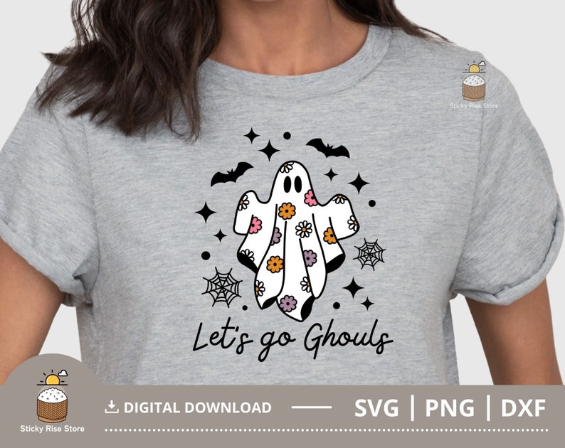 Pu&ograve; includere: Una maglietta grigia con un design di fantasma bianco e nero con fiori rosa e arancioni. Il testo "Let's go Ghouls" &egrave; stampato sotto il fantasma.