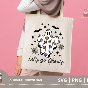 Pu&ograve; includere: Una borsa di tela bianca con un design di fantasma in bianco e nero. Il fantasma indossa un motivo floreale e il testo "Let's go Ghouls" &egrave; stampato sulla borsa.