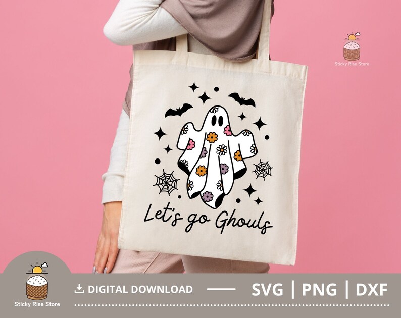 Pu&ograve; includere: Una borsa di tela bianca con un design di fantasma in bianco e nero. Il fantasma indossa un motivo floreale e il testo "Let's go Ghouls" &egrave; stampato sulla borsa.