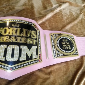 May include: A pink championship belt with gold accents and rhinestones. The center plate reads "World's Greatest Mom" and the side plate reads "Best Mom Ever".