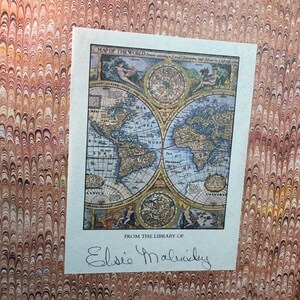 May include: A vintage map of the world, featuring detailed illustrations and cartography, is displayed on a cream-colored paper. The map is titled "Map of the World" and includes the inscription "From the Library of Elsie Malinsky". The background has a marbled pattern.