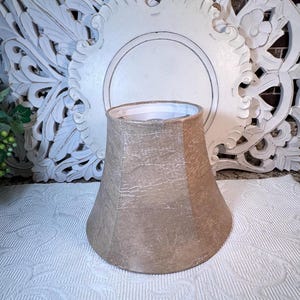 May include: A beige lampshade with a textured finish. The lampshade is shaped like a bell and has a white interior.