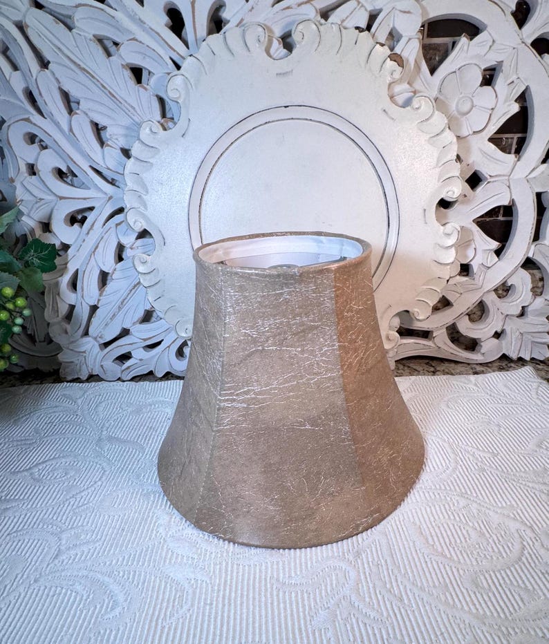 May include: A beige lampshade with a textured finish. The lampshade is shaped like a bell and has a white interior.