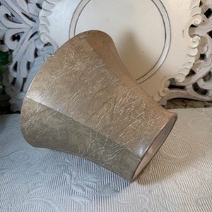 May include: A light brown, textured, ceramic planter with a wide, flared opening. The planter has a slightly distressed look, giving it a vintage feel.