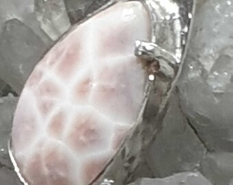 May include: A silver pendant featuring a white and pink agate stone. The stone has a distinctive pattern of white veins and swirls.