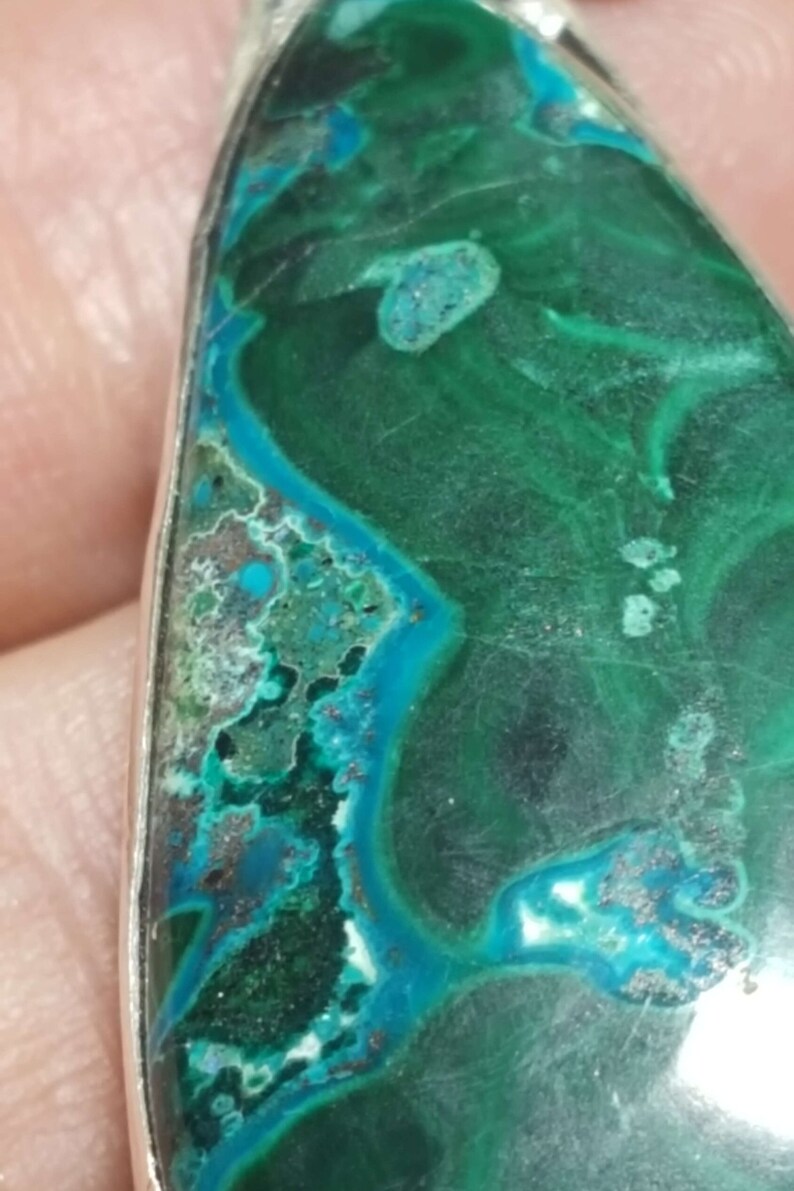 May include: A teardrop-shaped pendant featuring a green and blue malachite stone set in silver.