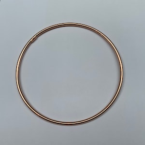 Könnte beinhalten: Ein schlichtes, roségoldenes Armkettchen. Das Armband besteht aus einem einzigen, dünnen Metallband.