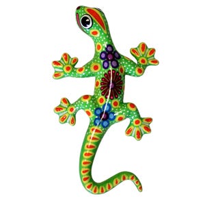 Peut inclure: Figurine décorative en forme de lézard, peinte à la main en vert avec des motifs floraux. Le design comprend des détails rouges, jaunes et bleus. Cet ornement coloré est un ajout vibrant à toute maison. La longueur du lézard est d'environ 20 cm.