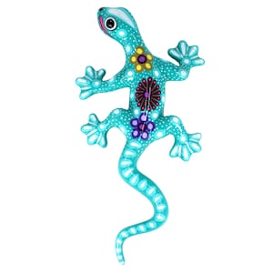 Könnte beinhalten: Türkisfarbene Eidechsenfigur mit weißen Tupfen und floralen Designs in Gelb, Rot und Lila. Die handgefertigte Eidechse hat einen langen Schwanz und ausgestreckte Gliedmaßen, ideal für die Heimdekoration.