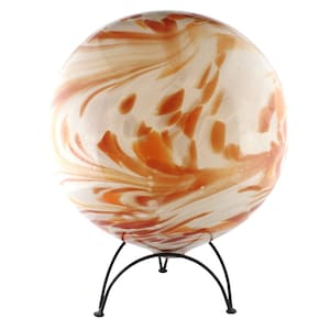 Könnte beinhalten: Dekorative Glaskugel mit cremefarbenem und orangefarbenem Wirbelmuster, auf einem schwarzen Metallständer. Das Design der Kugel weist opake und transluzente Abschnitte auf, die eine einzigartige visuelle Textur erzeugen. Der Ständer hat ein einfaches, dreibeiniges Design.