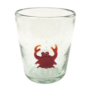 Puede incluir: Un vaso transparente de vidrio con un diseño de cangrejo de vidrio rojo. El vaso tiene una superficie texturizada.