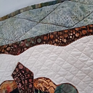 Peut inclure: Gros plan sur un tissu matelass&eacute; avec un motif brun et blanc. Le tissu est cousu en forme de losange. Le tissu est bord&eacute; d'une garniture brune.