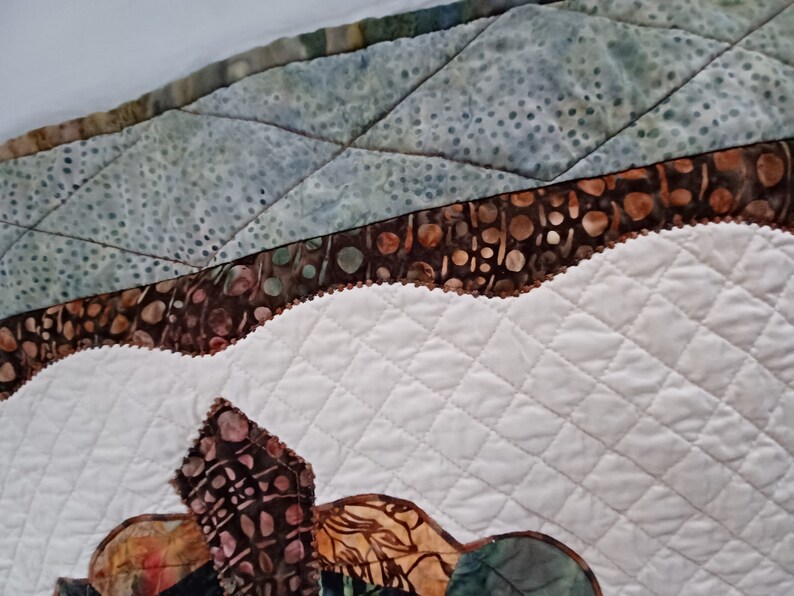 Peut inclure: Gros plan sur un tissu matelass&eacute; avec un motif brun et blanc. Le tissu est cousu en forme de losange. Le tissu est bord&eacute; d'une garniture brune.