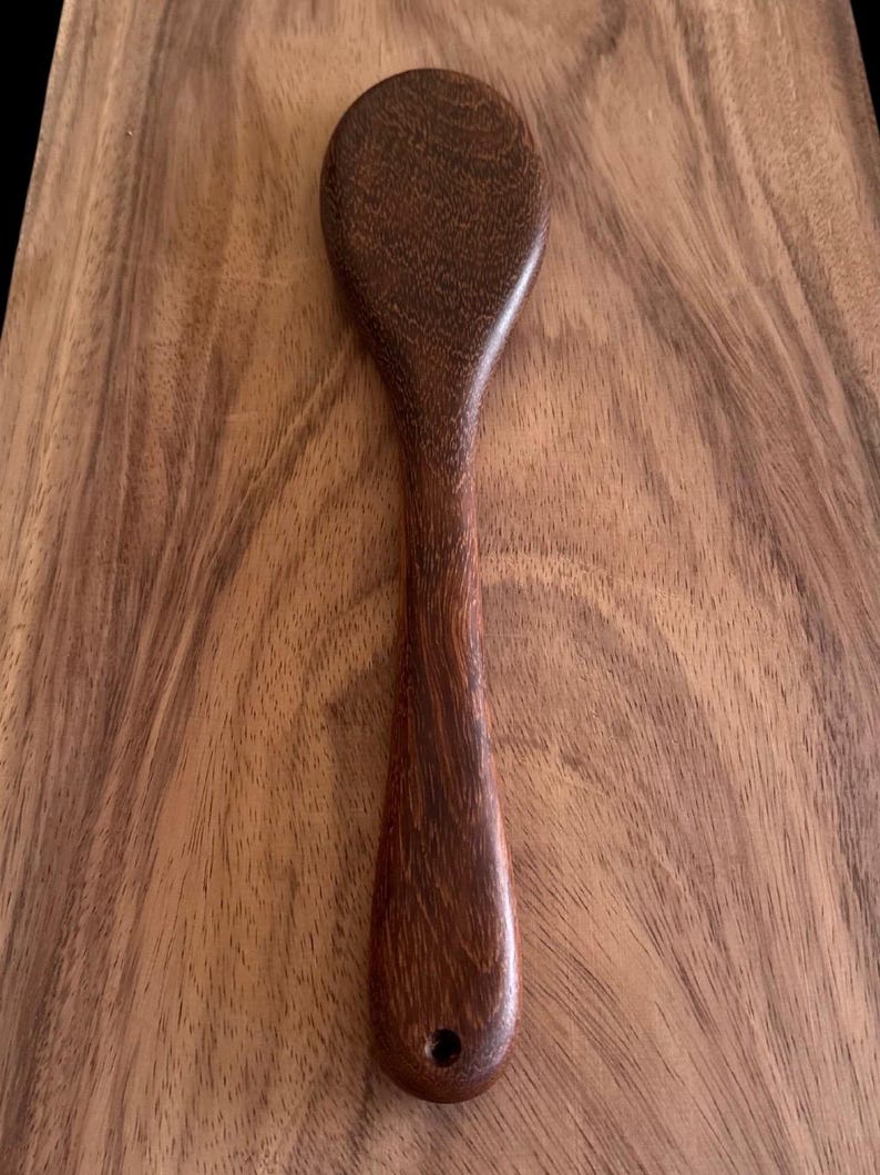 May include: A dark brown wooden spoon with a rounded bowl and a long, slender handle.